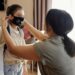 mother putting a face mask on her daughter